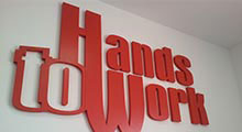 Logo Hands To Work w biurze firmy. Pomalowany styrodur.